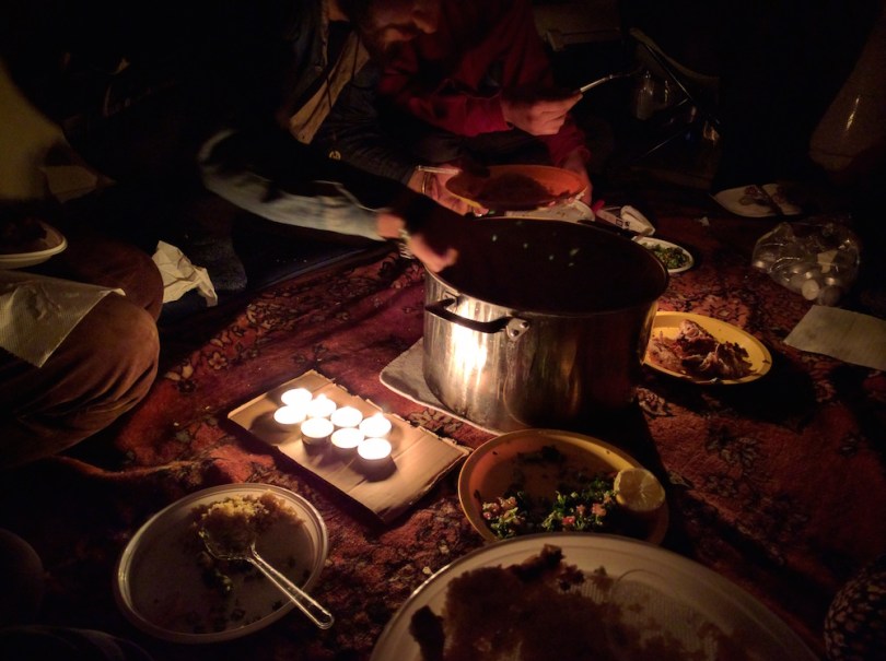 Sharing a meal with a group of volunteers and refugees cohabitating in a warehouse in northern Greece. No lights or electricity but high spirits abound