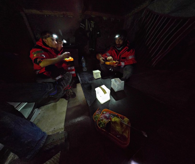 Volunteers share a meal at Korakas lighthouse by the light of headlamps